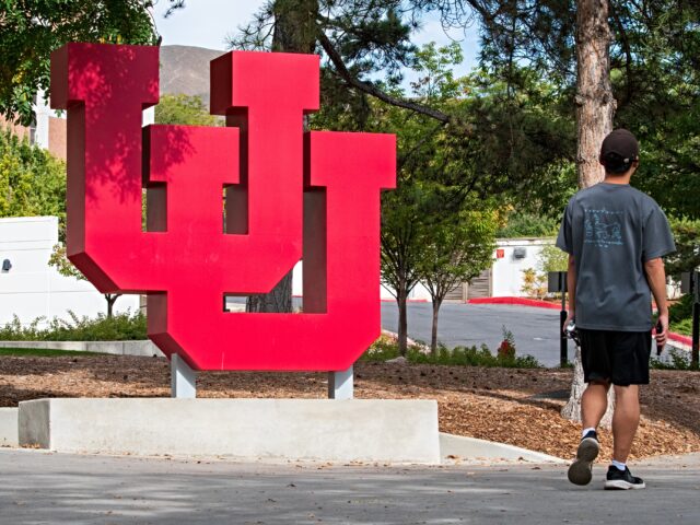 A student walks along an outdoor path near a large red interlocking ''UU'' sculptural monu