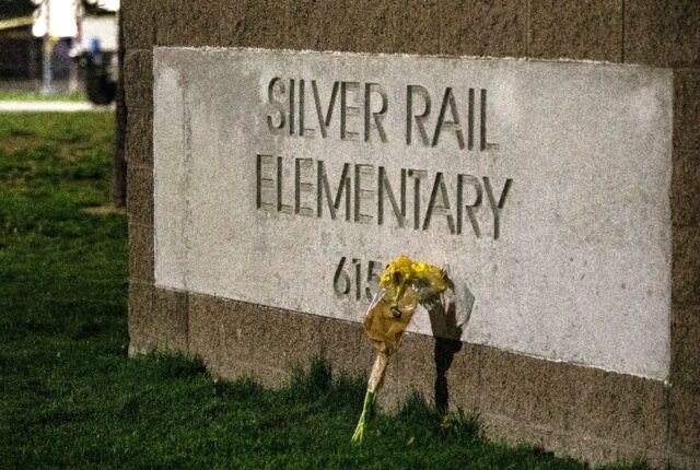 A flower bouquet rests against the sign outside the Silver Rail Elementary School followin