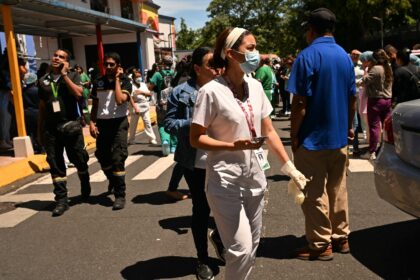 People check their mobile phones outside the maternity ward of Panama City's Santo To