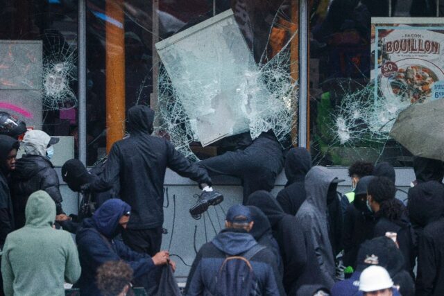 Protesters break the windows of a French frozen-food store in Paris