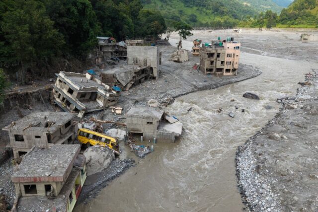 A torrent of muddy water surges past houses in the aftermath of flash floods in Nepal'
